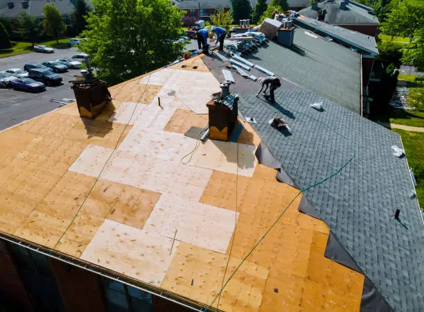 Roofer inspecting worn shingles on a Plano home before repair planning