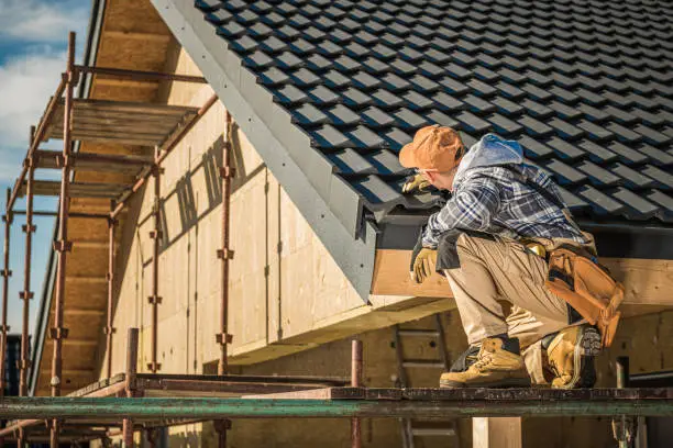 Experienced roofer inspecting flashing, vents, and shingle wear with close attention, Skilled roofer assessing roof wear patterns and flashing performance before repair planning, Experienced roofer inspecting flashing, shingles, and ventilation on steep residential roof